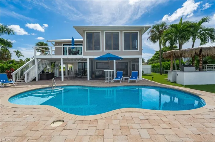 View of pool featuring a patio, stairs, and outdoor dining space - Virtually Edited Image