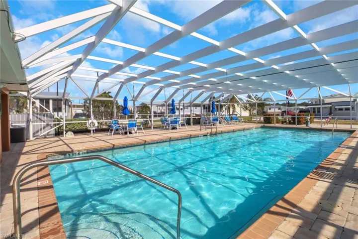 View of swimming pool with glass enclosure and a patio area