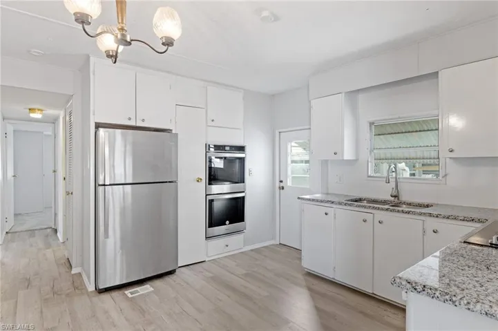 Kitchen with sink, white cabinets, pendant lighting, and appliances with stainless steel finishes
