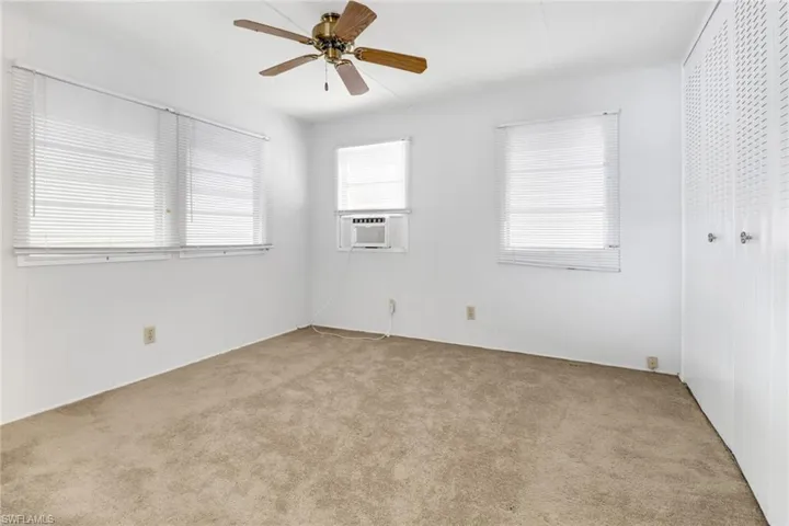 Unfurnished room with ceiling fan, cooling unit, and light colored carpet