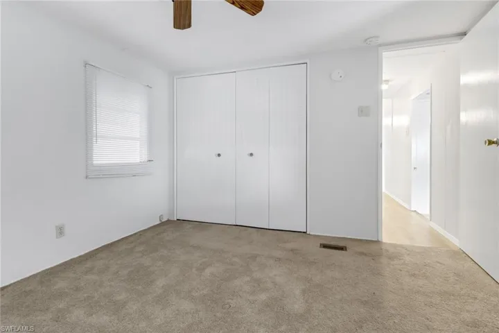 Unfurnished bedroom featuring ceiling fan, a closet, and light colored carpet