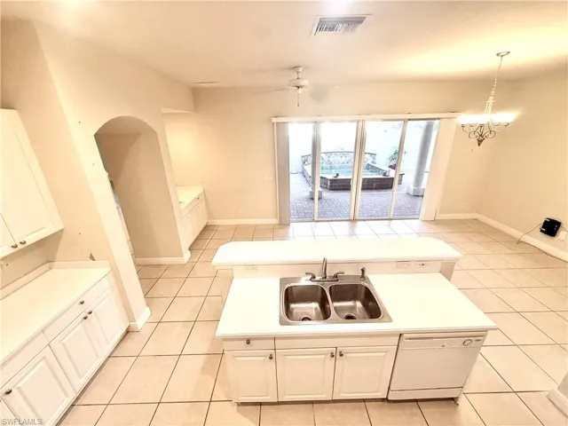 Kitchen featuring light countertops, a kitchen island, ceiling fan, and white cabinetry