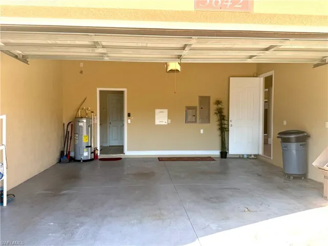 Garage with electric panel, water heater, and a garage door opener and entry into Courtyard