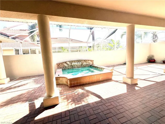 View of patio / terrace featuring a jacuzzi, glass enclosure, and a sunroom