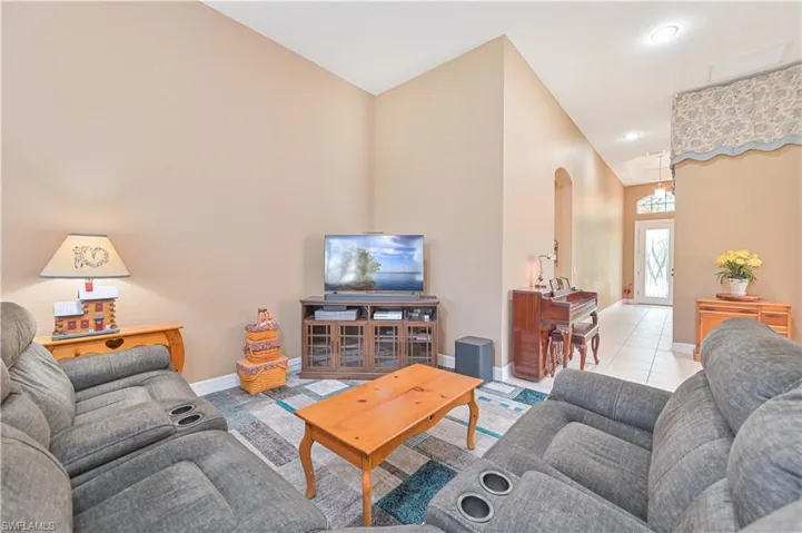 Living room featuring arched walkways, tile patterned floors, and recessed lighting