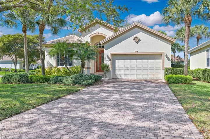 Mediterranean / spanish-style home featuring a front lawn, an attached garage, decorative driveway, and stucco siding