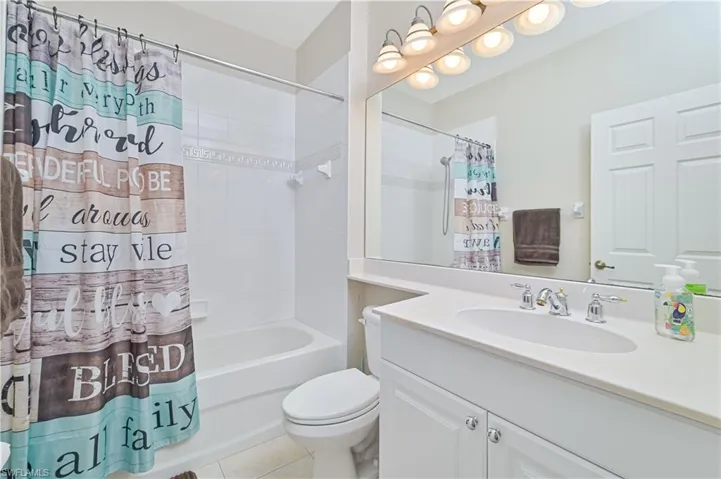 Bathroom featuring vanity, shower / bath combo, and light tile patterned floors