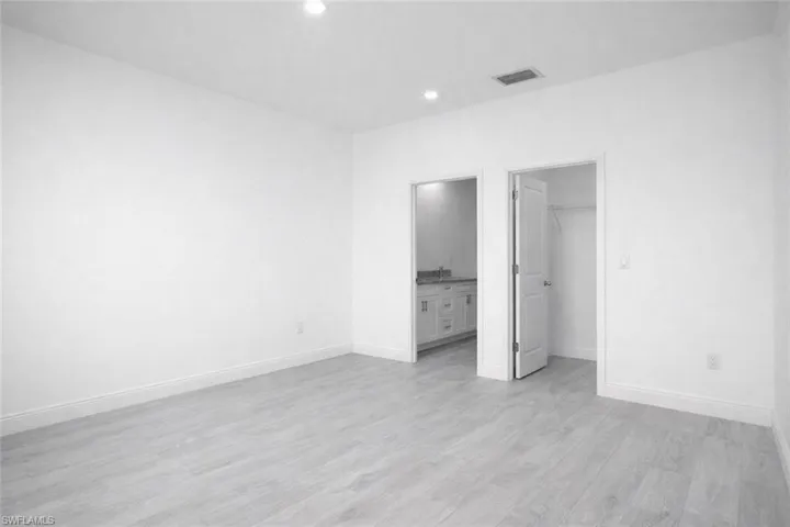 Spacious interior with neutral white walls, recessed ceiling lighting, light wood-finish flooring, and white baseboards