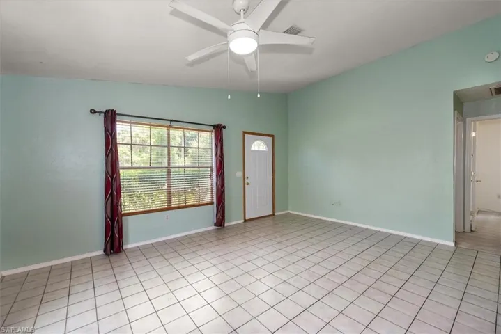 Empty room with ceiling fan and light tile patterned flooring
