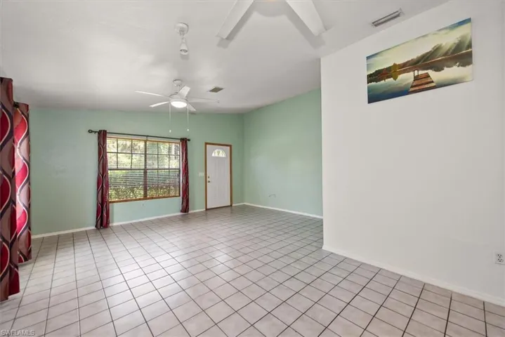 Unfurnished room with a ceiling fan, vaulted ceiling, and light tile patterned floors