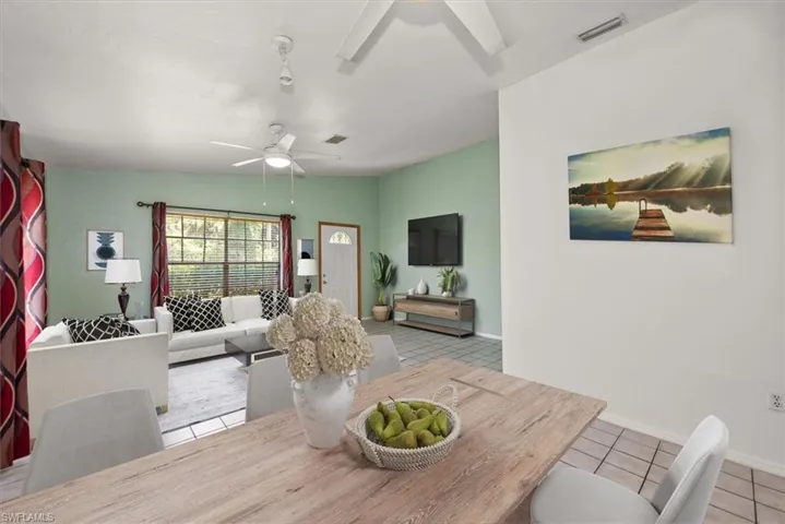 Dining room featuring light tile patterned floors, vaulted ceiling, and a ceiling fan