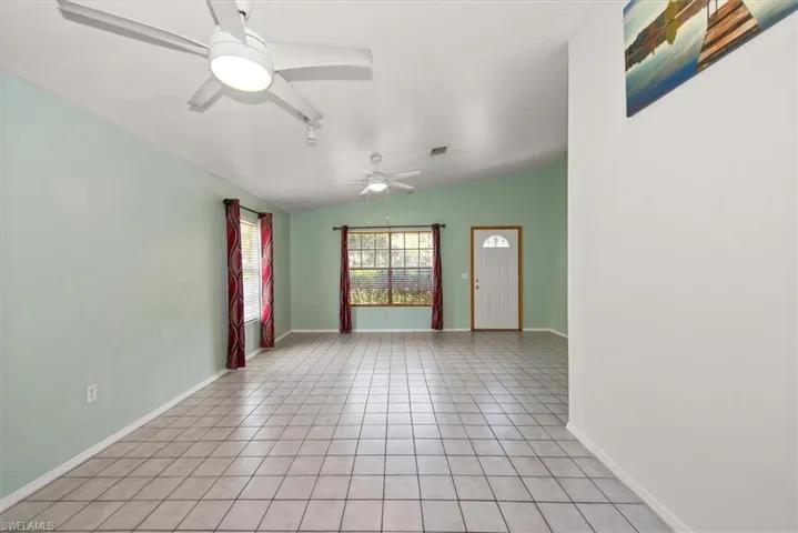 Unfurnished room with light tile patterned floors, ceiling fan, and vaulted ceiling