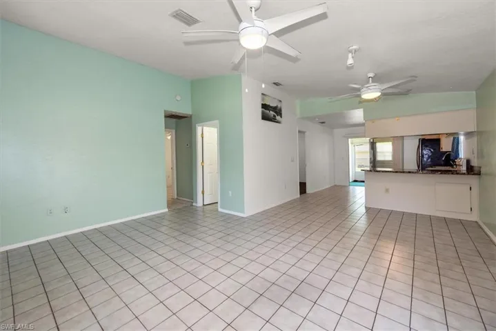 Unfurnished living room featuring light tile patterned floors, a ceiling fan, and vaulted ceiling