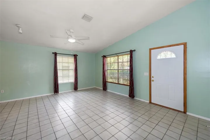 Foyer with a ceiling fan, vaulted ceiling, plenty of natural light, and light tile patterned floors