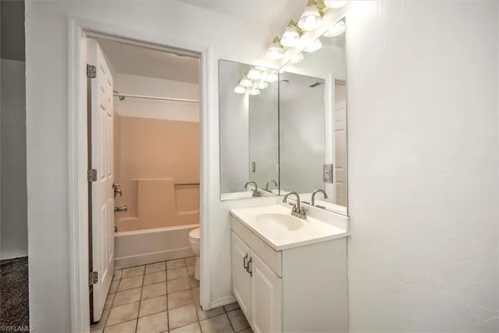 Bathroom featuring vanity, shower / tub combination, and light tile patterned floors