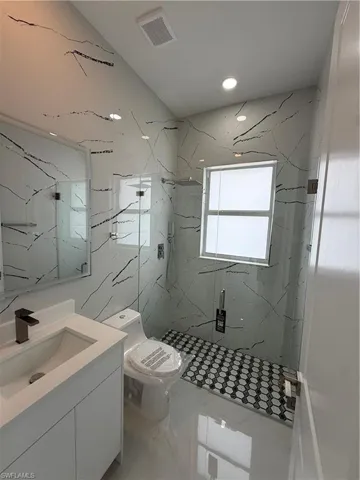 Bathroom with vanity and a marble finish shower