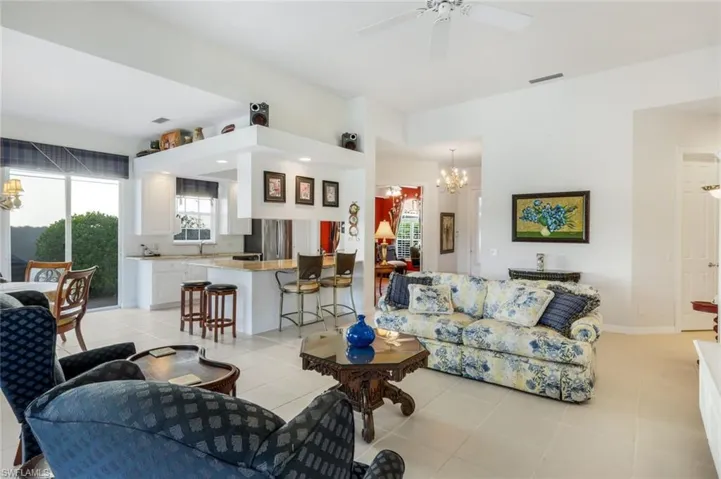 Tiled living room featuring ceiling fan with notable chandelier