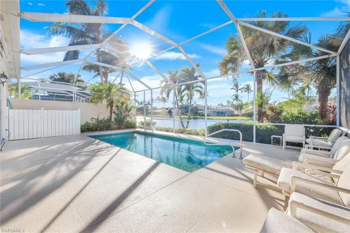 View of pool with a patio, a water view, and glass enclosure