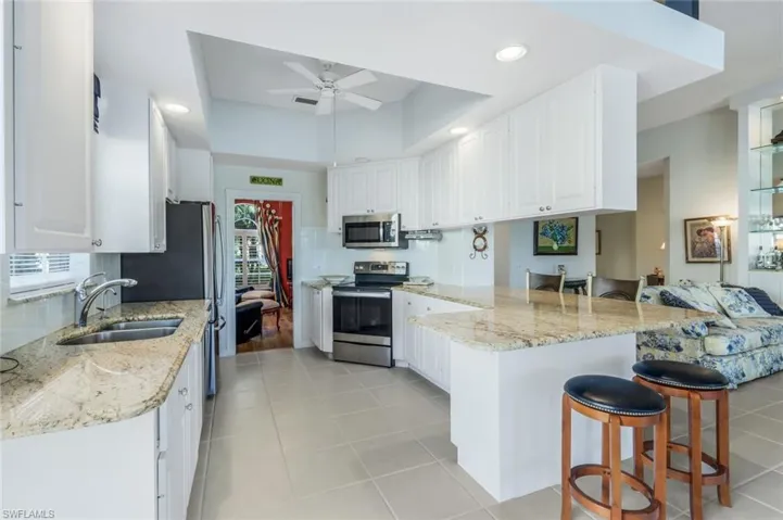 Kitchen featuring kitchen peninsula, appliances with stainless steel finishes, white cabinetry, and plenty of natural light