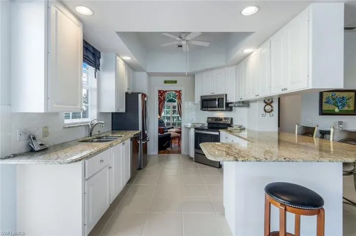 Kitchen featuring kitchen peninsula, a breakfast bar, stainless steel appliances, and white cabinetry