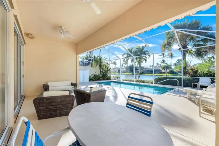 View of swimming pool featuring a lanai, ceiling fan, a water view, and a patio