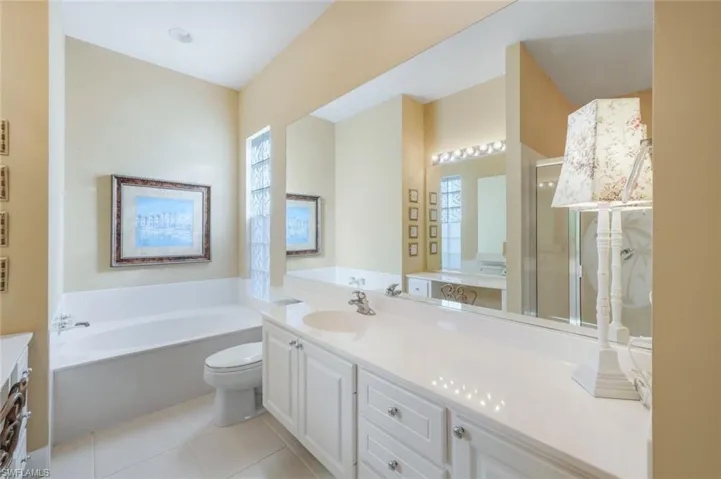 Bathroom featuring tile patterned floors, vanity, toilet, and a bath