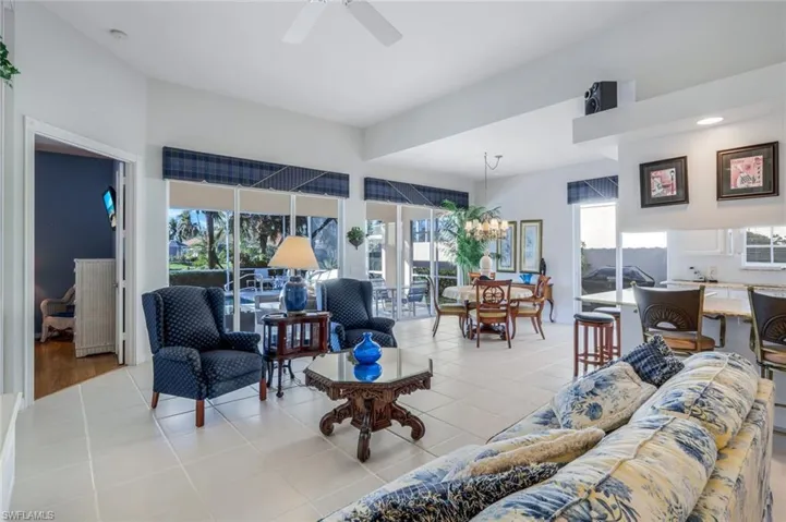 Tiled living room with ceiling fan with notable chandelier