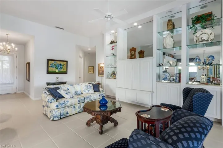 Living room featuring ceiling fan with notable chandelier and light tile patterned floors