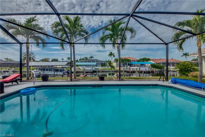 View of swimming pool featuring a boat dock, a water view, and glass enclosure