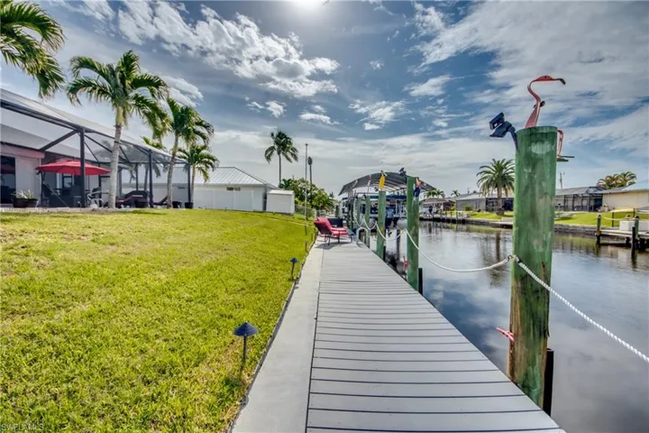 Dock area featuring a water view, glass enclosure, and a lawn