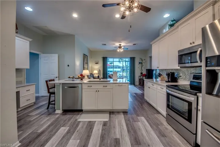 Kitchen with appliances with stainless steel finishes, light hardwood / wood-style floors, tasteful backsplash, and sink