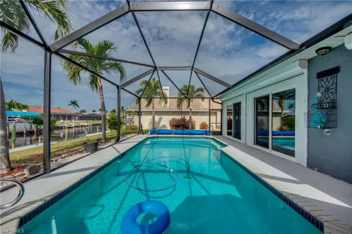 View of pool featuring glass enclosure and a water view