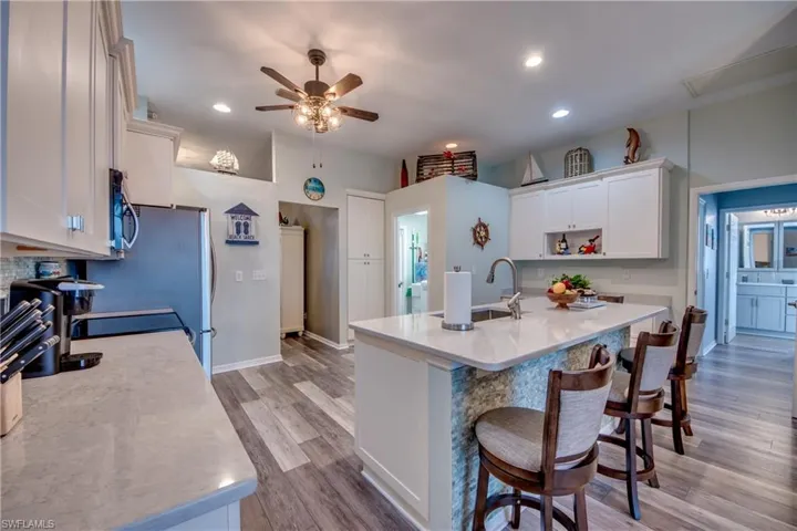 Kitchen featuring ceiling fan, sink, light hardwood / wood-style flooring, a breakfast bar area, and white cabinets