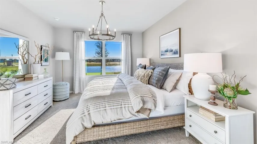 Model home. Bedroom featuring light carpet, a water view, and hanging lights
