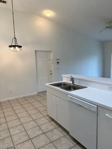 Kitchen area featuring a double basin stainless steel sink, a white dishwasher, and light-toned cabinetry