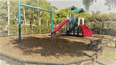 Recreational playground featuring a multi-level structure with two slides, a swing set frame, and a decorative park bench