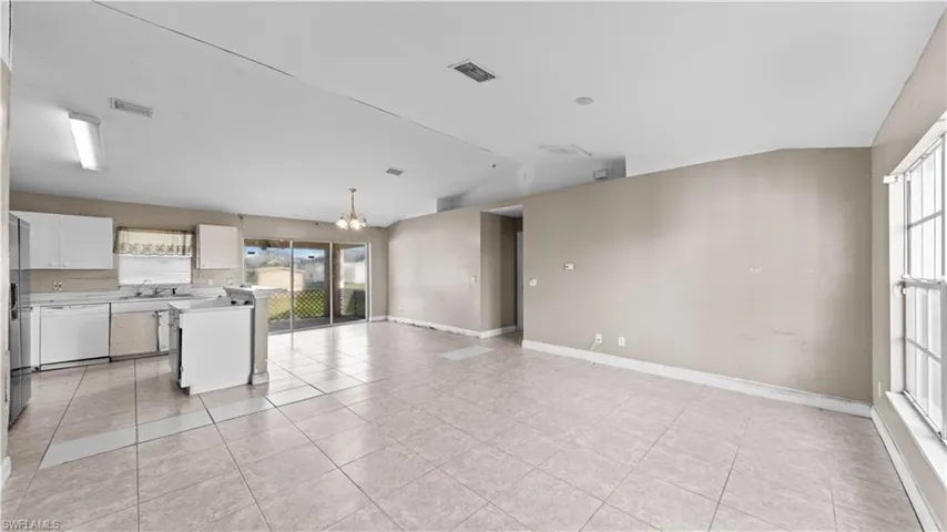 Kitchen featuring white cabinets, a chandelier, lofted ceiling, white dishwasher, and pendant lighting