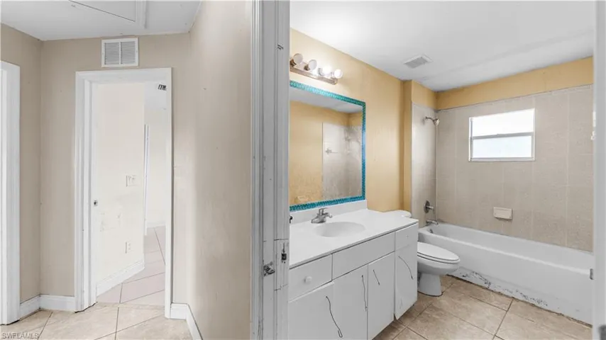 Full bathroom with vanity, light tile patterned floors, and washtub / shower combination