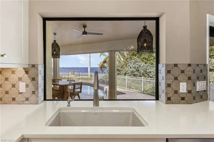 Kitchen featuring a water view, white cabinetry, ceiling fan, and sink