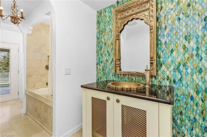 Bathroom featuring tile patterned floors, a chandelier, vanity, and a relaxing tiled tub