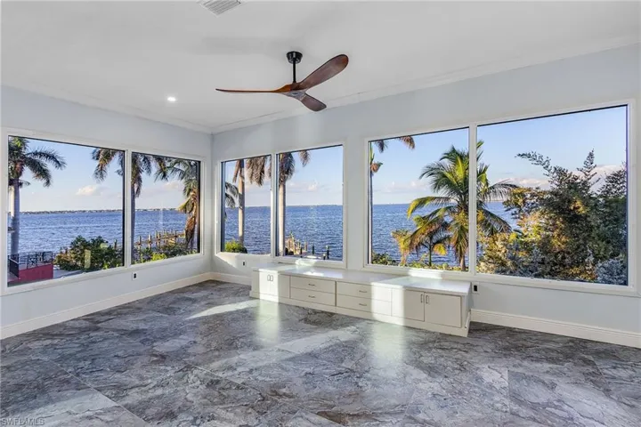 Unfurnished sunroom featuring a water view and ceiling fan