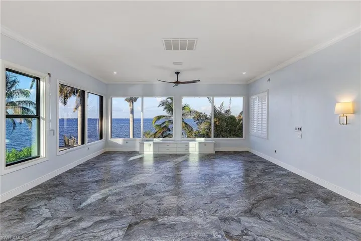 Unfurnished room featuring ceiling fan, a water view, and crown molding