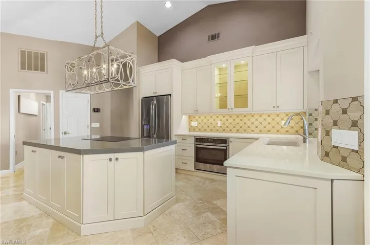 Kitchen with white cabinetry, sink, high vaulted ceiling, and appliances with stainless steel finishes
