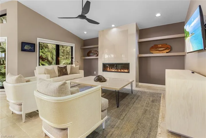 Living room featuring ceiling fan, a fireplace, lofted ceiling, and tile patterned flooring