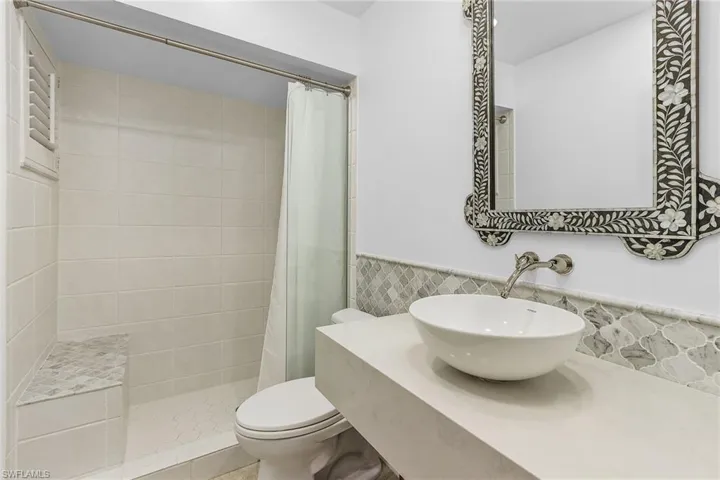 Bathroom with toilet, tile walls, curtained shower, and sink