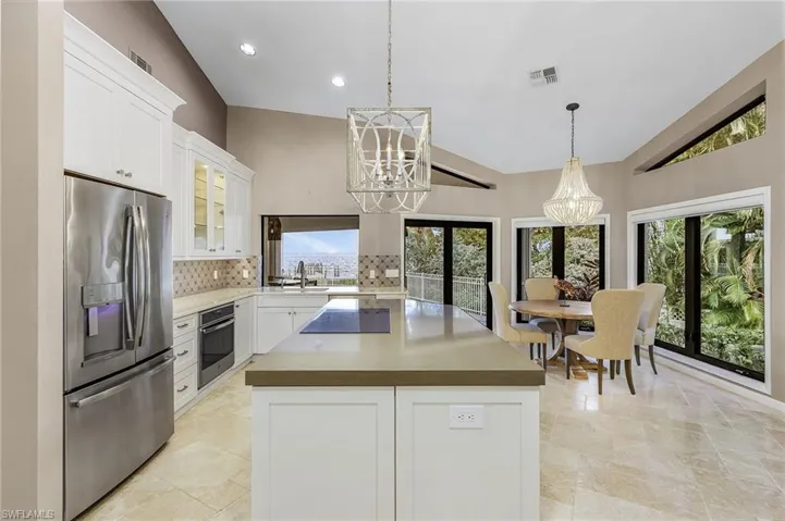 Kitchen featuring white cabinetry, a center island, stainless steel appliances, an inviting chandelier, and vaulted ceiling