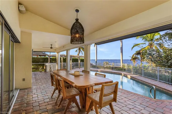 Sunroom featuring a wealth of natural light, a swimming pool, a water view, and vaulted ceiling