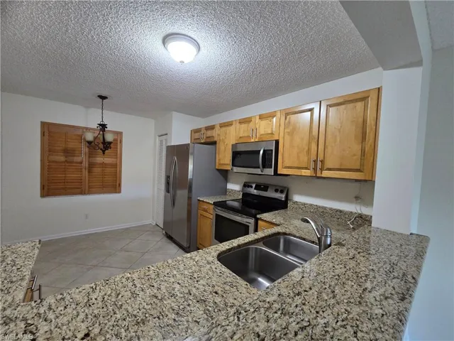 Kitchen featuring sink, hanging light fixtures, granite countertops, kitchen peninsula, and stainless-steel appliances.