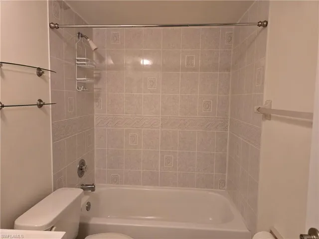 Bathroom with tiled shower / bath and toilet