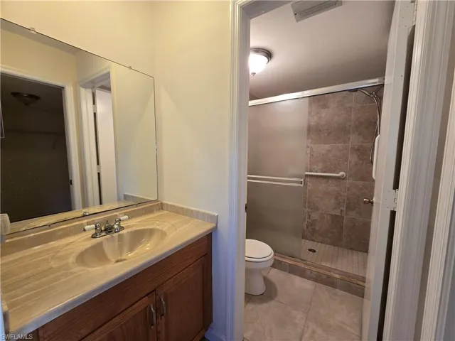 Bathroom with tile patterned floors, vanity, toilet, and a shower with shower door